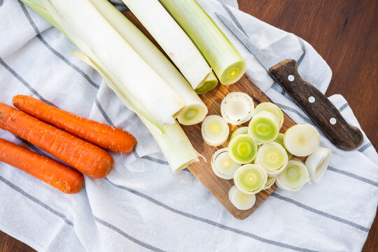 Fresh leeks sliced on board with knife and carrots