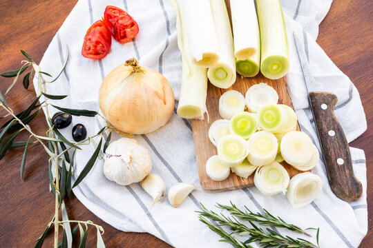 Fresh leeks with onion, garlic and herbs on kitchen towel