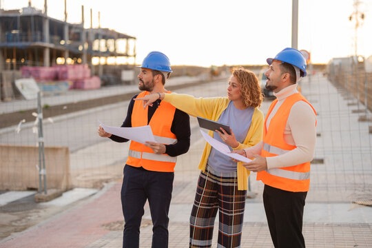 Architect and workers reviewing plans at construction site