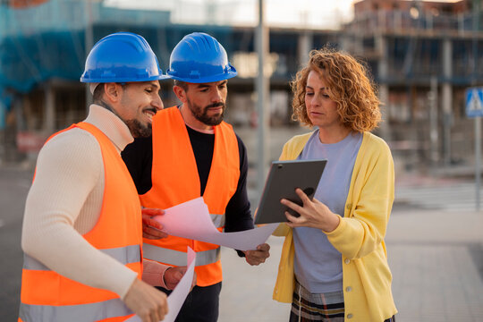 Architect and workers reviewing plans with tablet on site