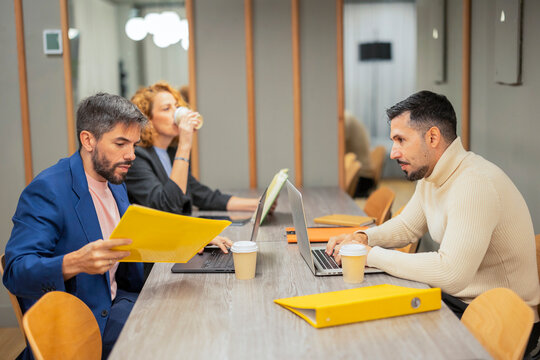Coworking workers reviewing documents and laptops at table
