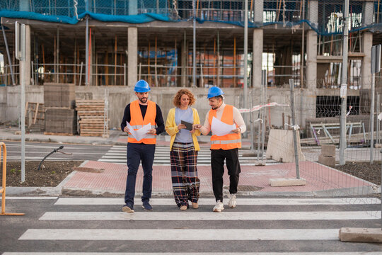 Architect and construction workers reviewing plans on site