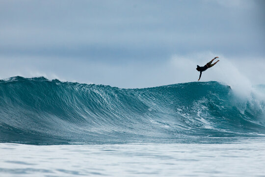Surfer launching off a powerful ocean wave at sunrise