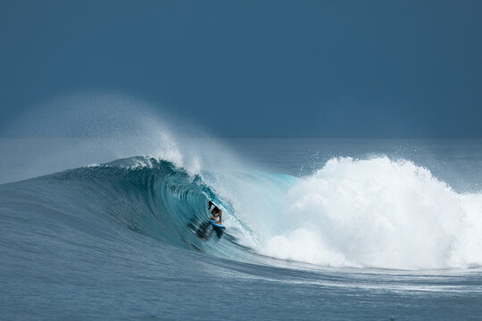 Surfer riding inside a barreling ocean wave with sea spray
