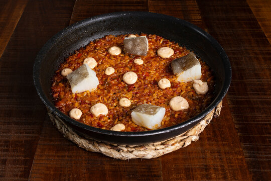 Spanish rice in paella pan with cod and aioli sauce