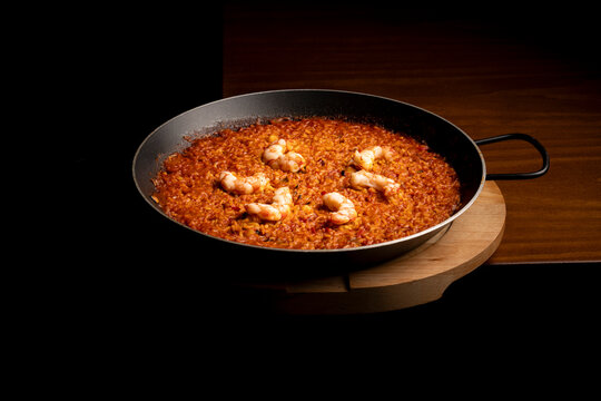 Spanish seafood rice in paella pan on dark background