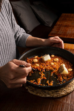 Person eating Spanish rice paella with cod and aioli