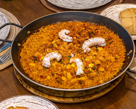 Spanish seafood rice in paella pan on rustic table setting