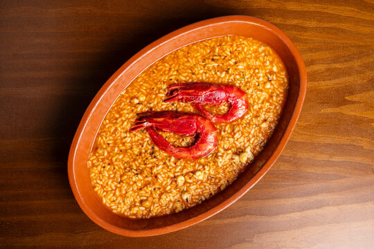 Spanish seafood rice stew in clay dish on wooden table
