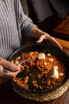 Person eating Spanish rice paella with cod and aioli