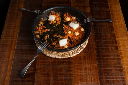 Spanish rice paella pan with cod and aioli on table