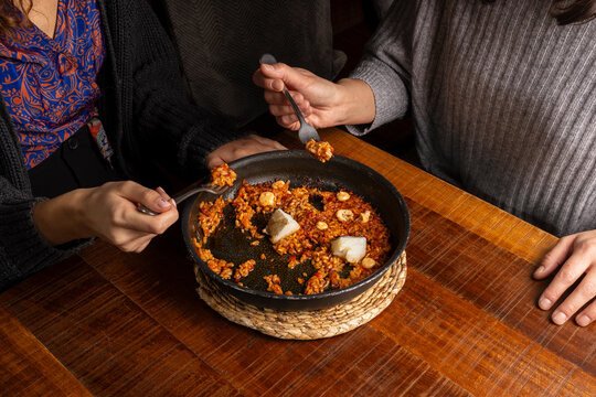 Spanish rice paella pan with cod, aioli, and diners