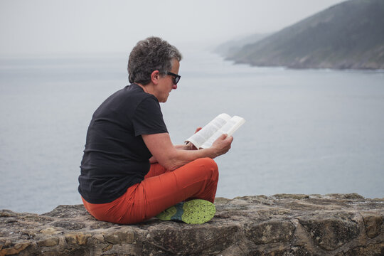 Senior woman reading by the seaside