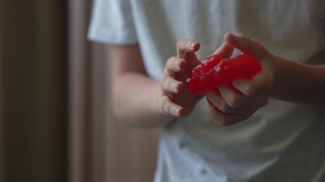 A child plays with homemade red slime. A fun sensory activity, stress relief, fine motor development, and a concept for educational content, toy stores, and home child development. 