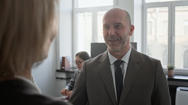 Over shoulder view of anonymous woman communicating with Caucasian colleague in meeting room