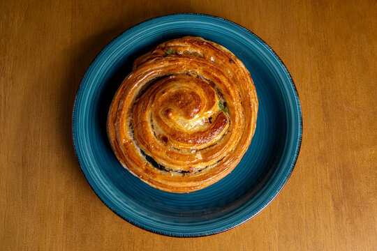 Fresh baked spiral pastry on blue plate for breakfast