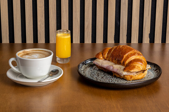 Morning breakfast with ham croissant, coffee and orange juice