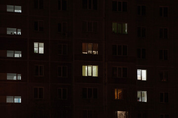 Obraz premium Lights in some windows of a high-rise building, late at night, in energy-saving mode, running on generators to avoid a blackout