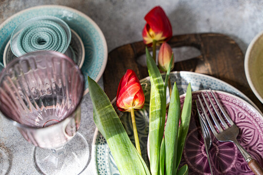 Red tulips table setting with rustic plates and glassware