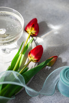 Red tulips on table with ribbon and glass, soft light