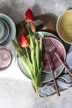 Red tulips on table with rustic dinnerware flat lay