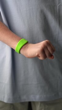 A teenager in a hotel room puts on an RFID or NFC bracelet. A boy puts on a contactless bracelet on his wrist. High quality FullHD footage