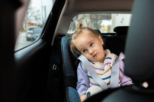 Tired girl in car seat looking out window on ride