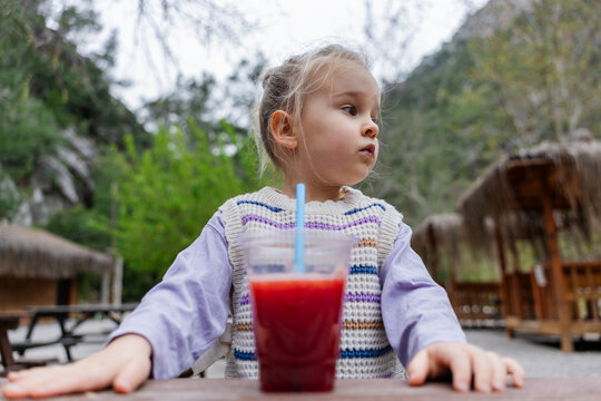 Toddler sitting at outdoor table with juice in nature