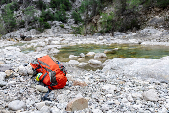 Mountain adventure backpack by clear river on rocky shore
