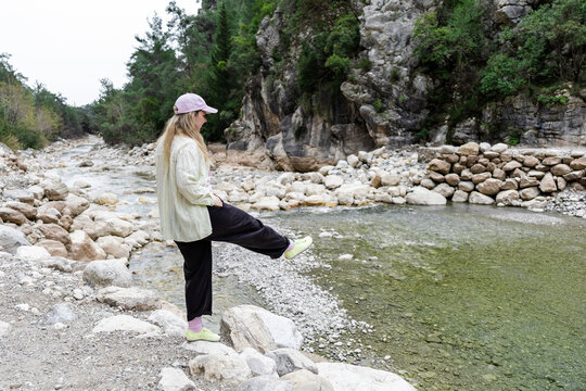 Woman hiker by mountain stream in rocky canyon landscape