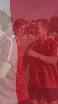 Vertical video: Red shirts moving, front player patting shoulders for sports, red overlay over team