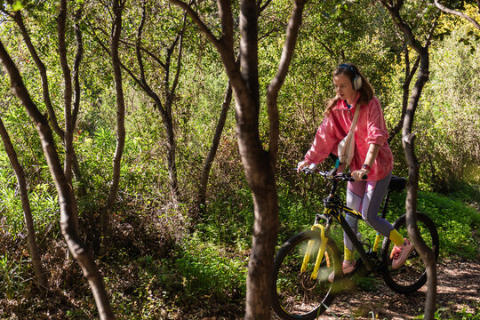 Woman cycling with headphones in a green park