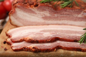 Obraz premium Pieces of smoked bacon and rosemary on wooden board, closeup