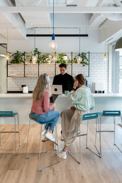 Coworking team meeting at office kitchen counter with laptop