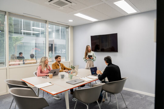 Coworking team meeting with laptop and presentation screen