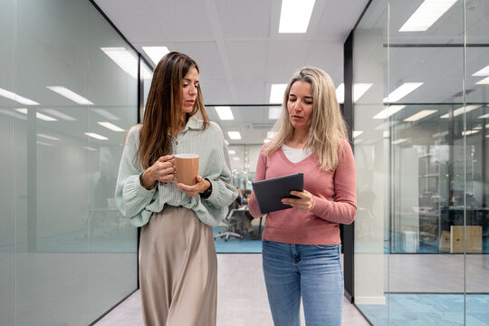 Coworking colleagues discuss project update on tablet