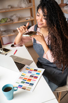 Potter in workshop photographing ceramic glaze sample tile