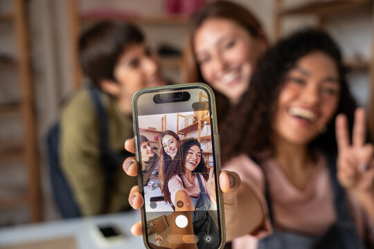 Friends taking smartphone selfie in a pottery workshop studio