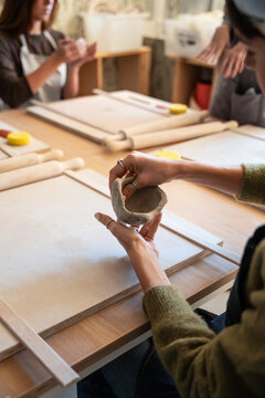 Hands shaping clay bowl in a pottery workshop class
