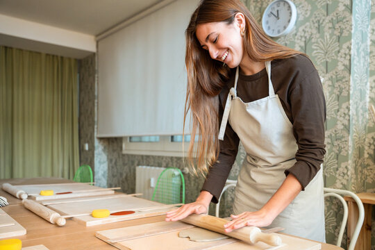 Woman rolling clay at pottery workshop table indoors