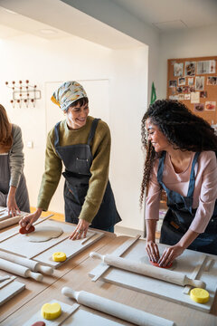 Pottery workshop students shaping clay slabs with rolling pins
