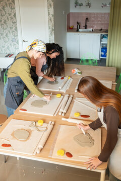Women shaping clay slabs in a pottery workshop class indoors