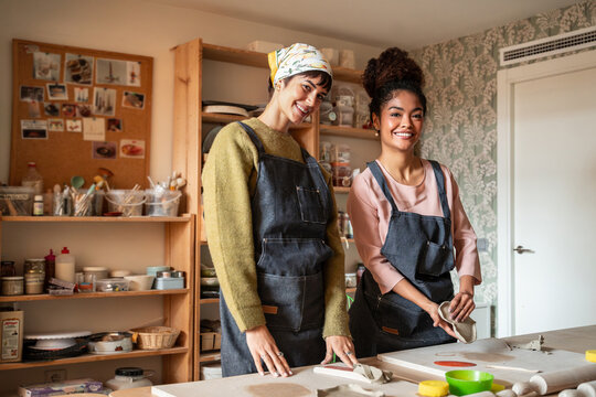 Two women in apron at pottery workshop studio table