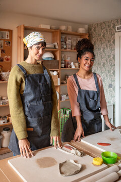 Two women potters in a pottery workshop studio, smiling