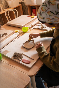 Hands shaping clay slab at pottery workshop table indoors