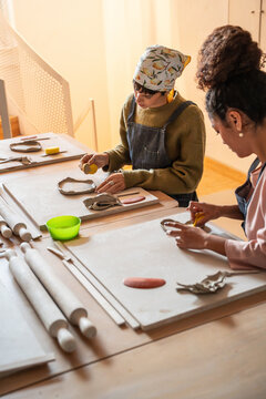 Two women shaping clay in a pottery workshop studio