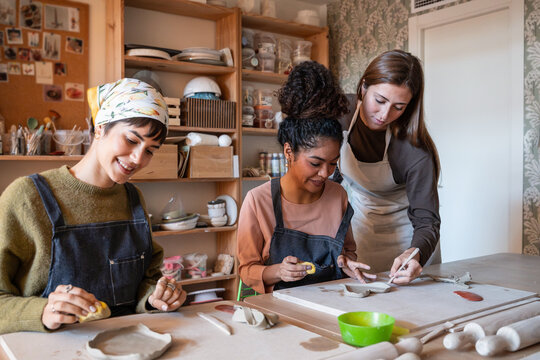 Pottery workshop lesson with instructor guiding clay work