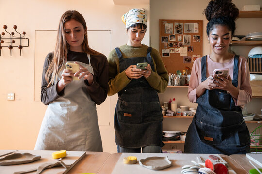 Pottery workshop artists using phones during studio break