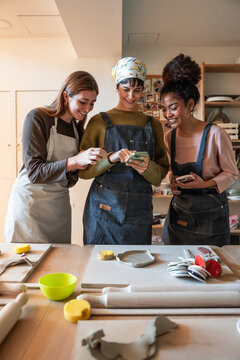 Friends using smartphone during pottery workshop class