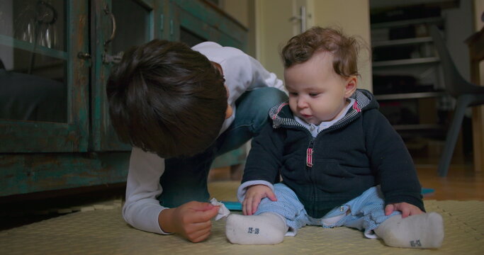 Young boy helping baby brother by wiping his nose with tissue, sweet moment of sibling affection, showing tenderness, care, empathy and warmth in everyday family life
